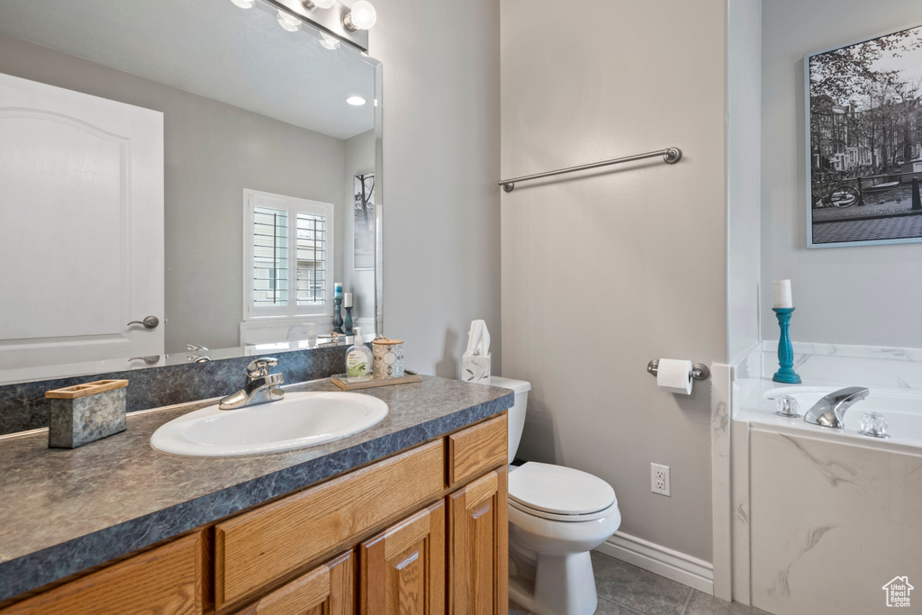Bathroom featuring vanity with extensive cabinet space, a bathtub, tile flooring, and toilet