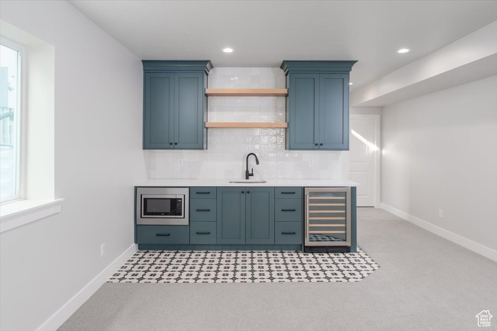 Bar featuring sink, stainless steel microwave, beverage cooler, and tasteful backsplash