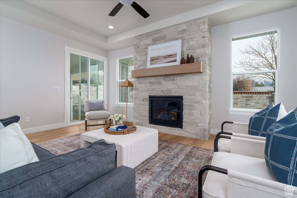 Living room with a fireplace, ceiling fan, a healthy amount of sunlight, and light wood-type flooring