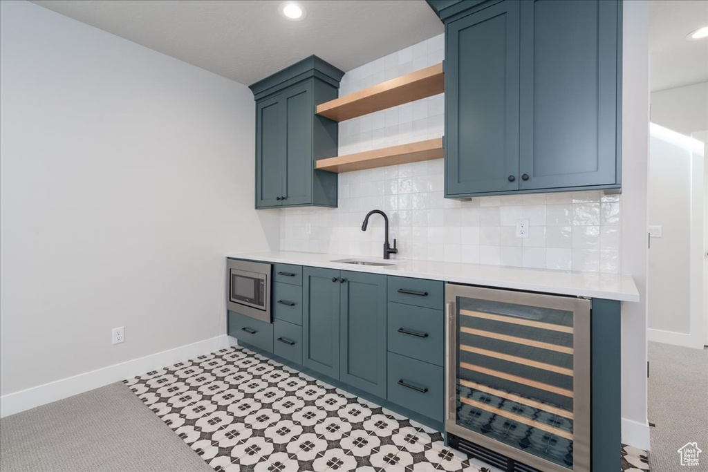 Kitchen with wine cooler, stainless steel microwave, backsplash, and sink