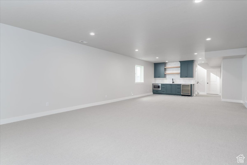 Unfurnished living room with sink and light colored carpet