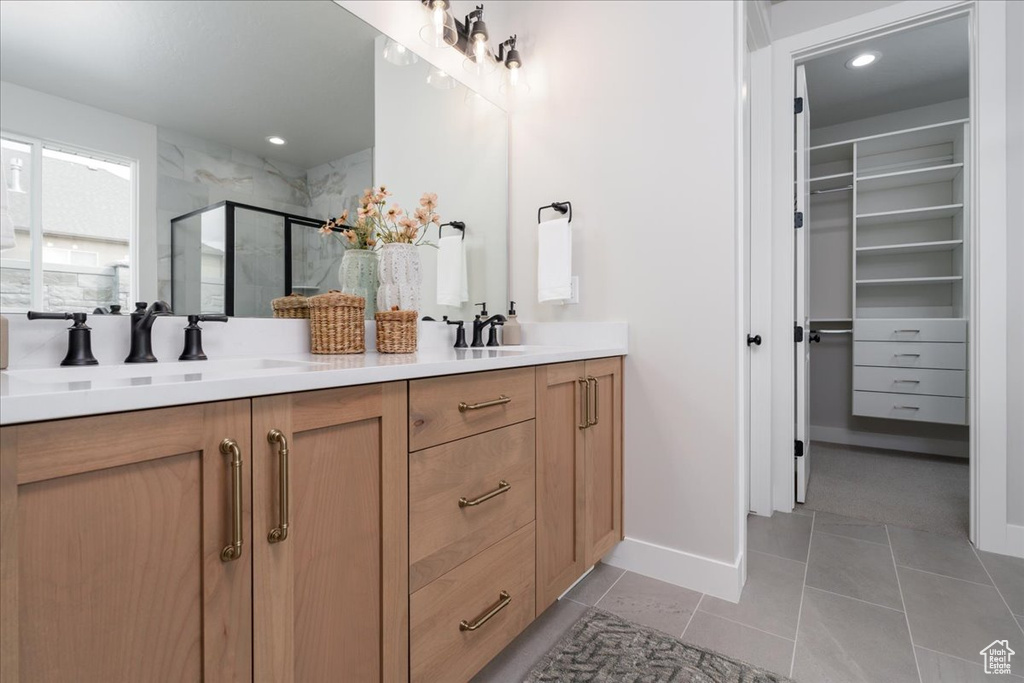 Bathroom with dual vanity, tile flooring, and a shower with door