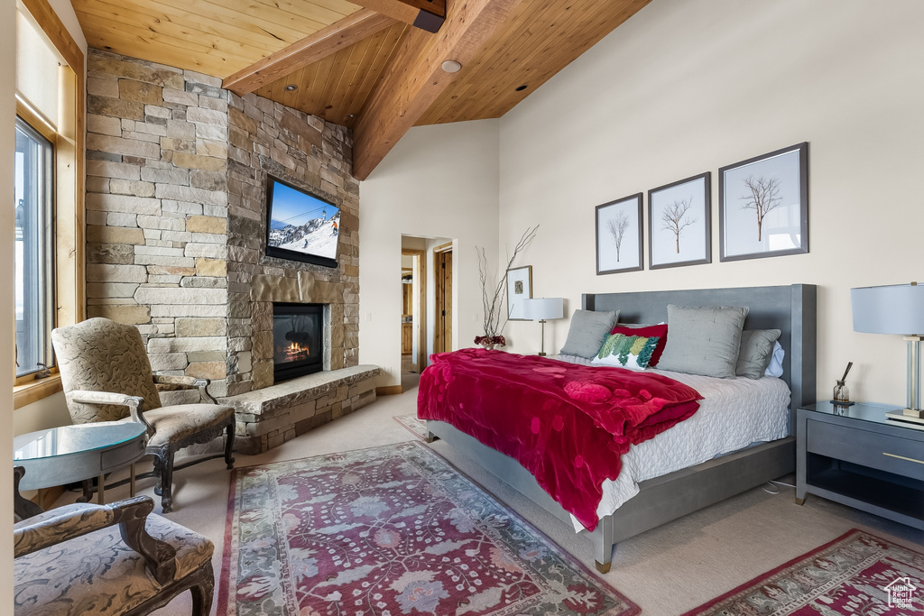 Bedroom with multiple windows, a stone fireplace, wood ceiling, and light colored carpet