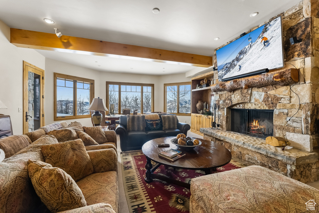 Living room featuring a stone fireplace and beam ceiling