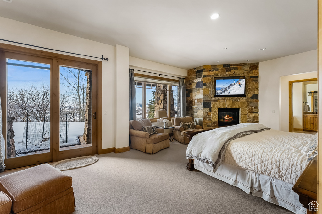 Carpeted bedroom featuring a stone fireplace and access to exterior