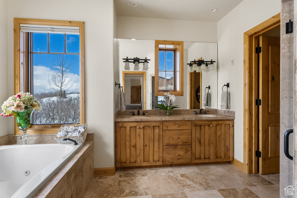 Bathroom with large vanity, tile floors, dual sinks, and tiled tub