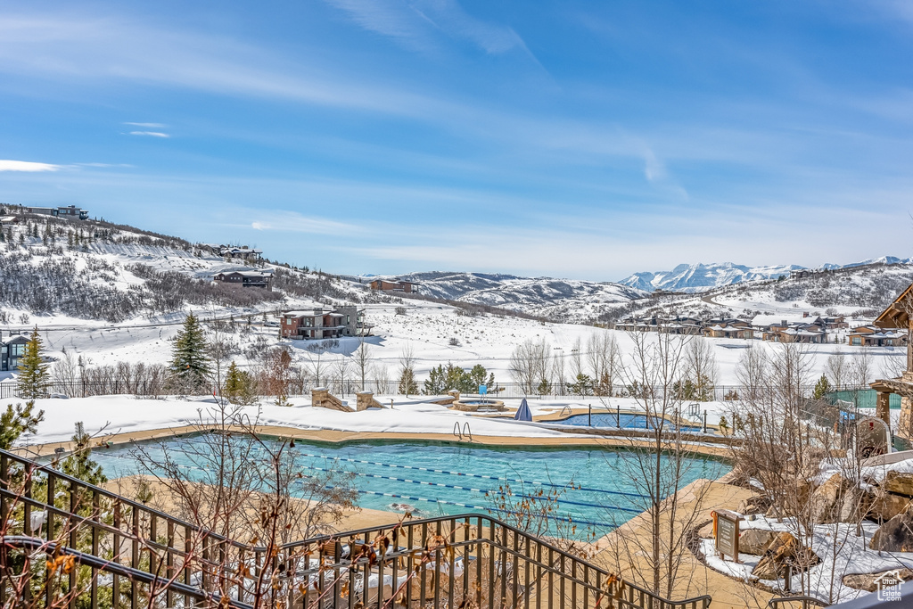 Snow covered pool with a mountain view and a patio area