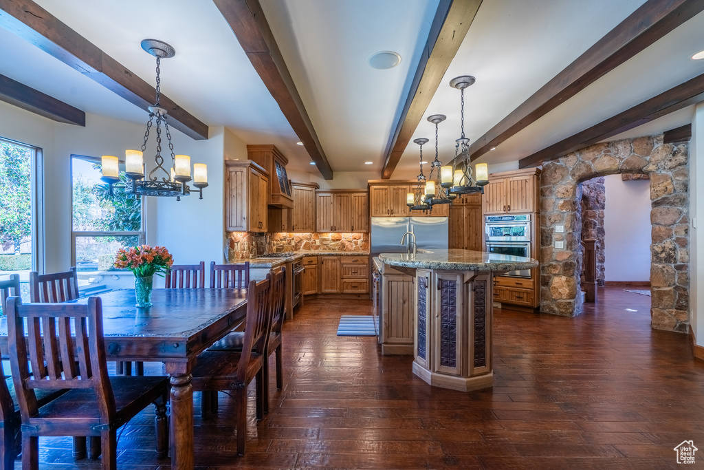 Dining space with dark hardwood / wood-style floors, beam ceiling, and a notable chandelier