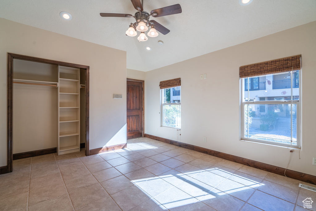 Unfurnished bedroom featuring light tile flooring, a closet, and ceiling fan