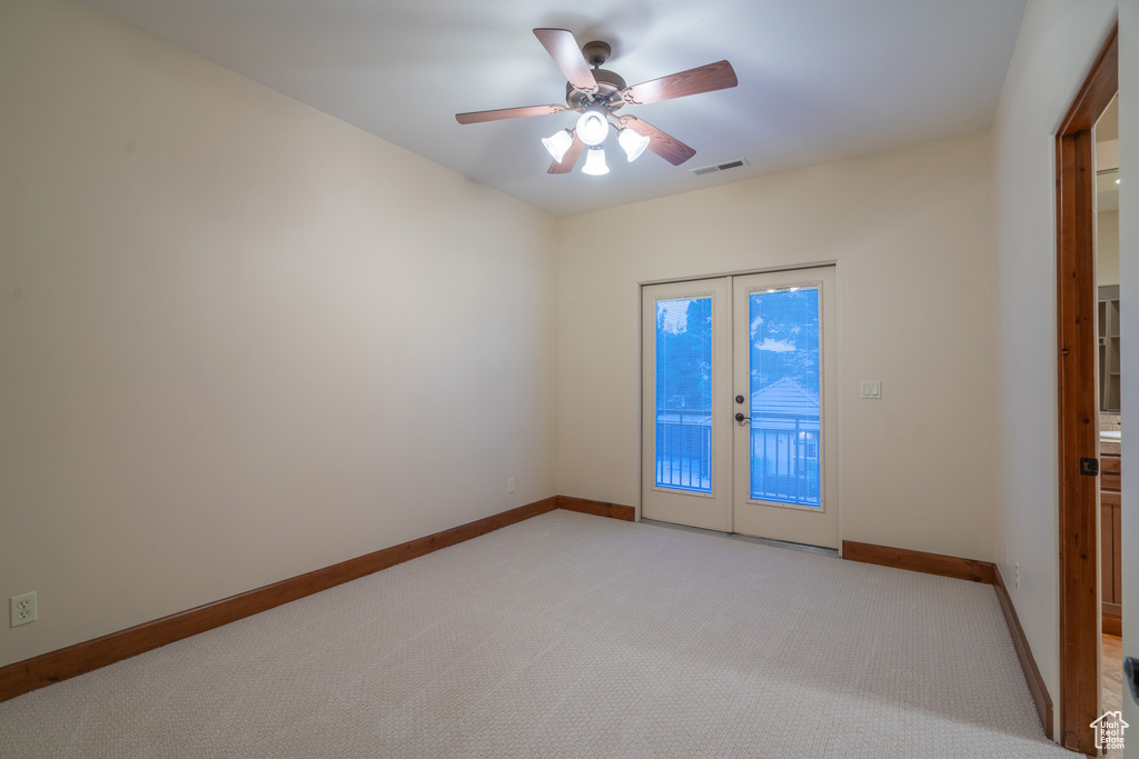Carpeted empty room featuring ceiling fan and french doors