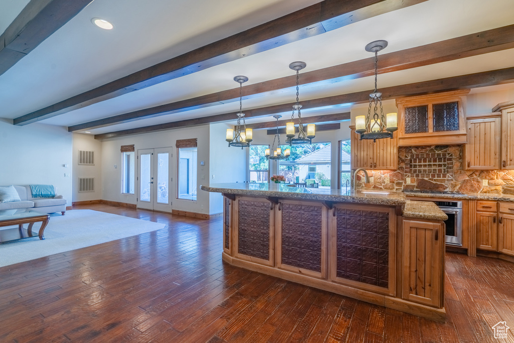 Kitchen with hanging light fixtures, beam ceiling, dark hardwood / wood-style floors, and tasteful backsplash