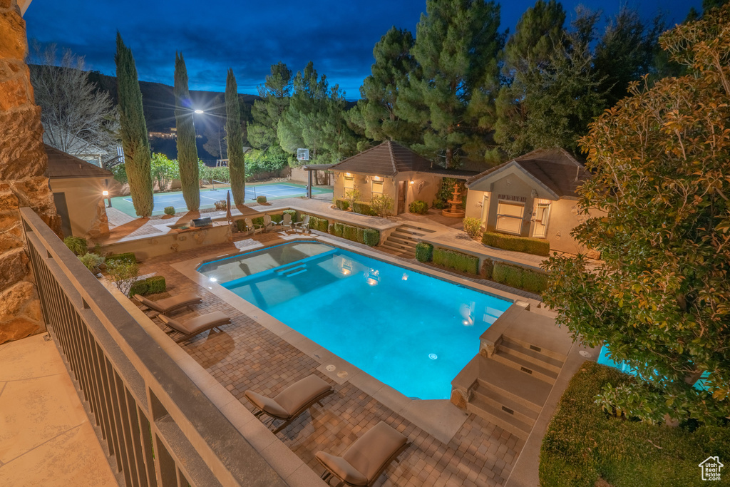 Pool at twilight with a patio area and an outdoor structure