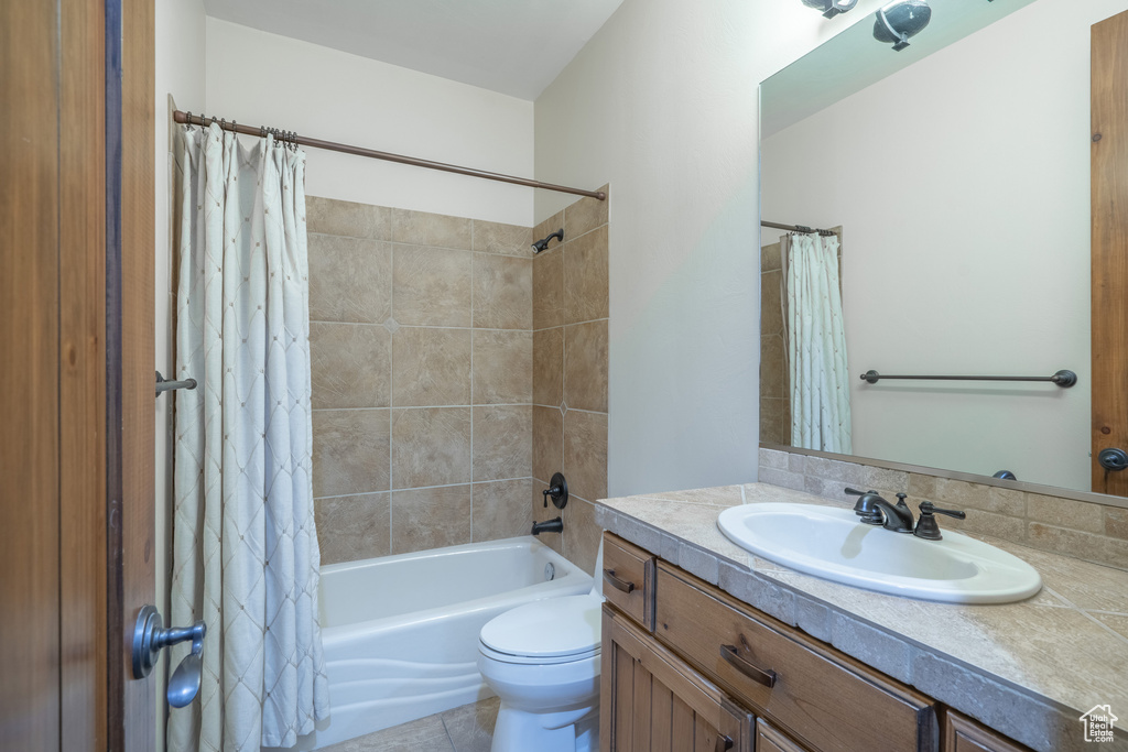 Full bathroom featuring toilet, tile floors, oversized vanity, and shower / bath combo with shower curtain