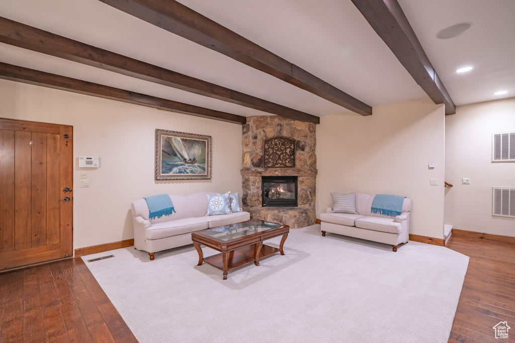 Living room featuring a fireplace, dark hardwood / wood-style flooring, and beam ceiling