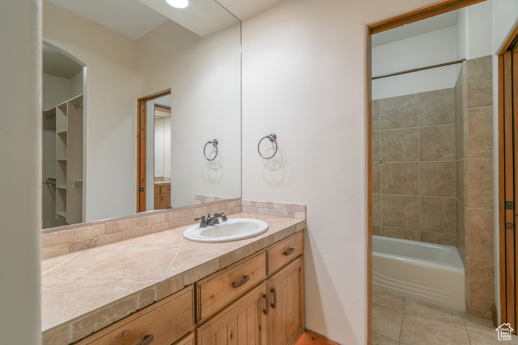 Bathroom with tiled shower / bath combo, tile floors, and oversized vanity
