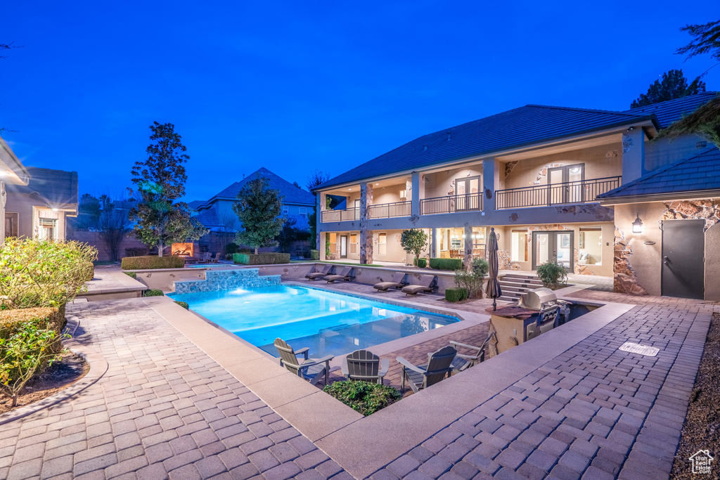Pool at twilight with a patio area and exterior kitchen