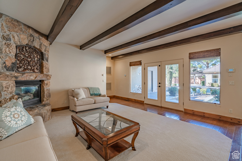 Living room featuring a fireplace, light hardwood / wood-style flooring, beam ceiling, and french doors