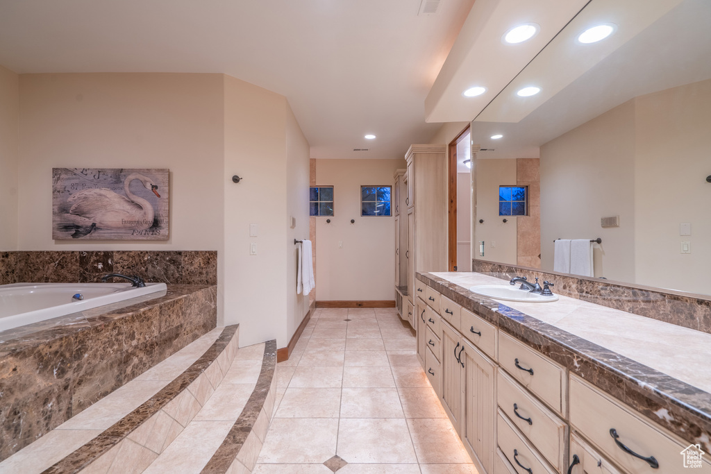 Bathroom featuring large vanity, tile floors, and tiled bath