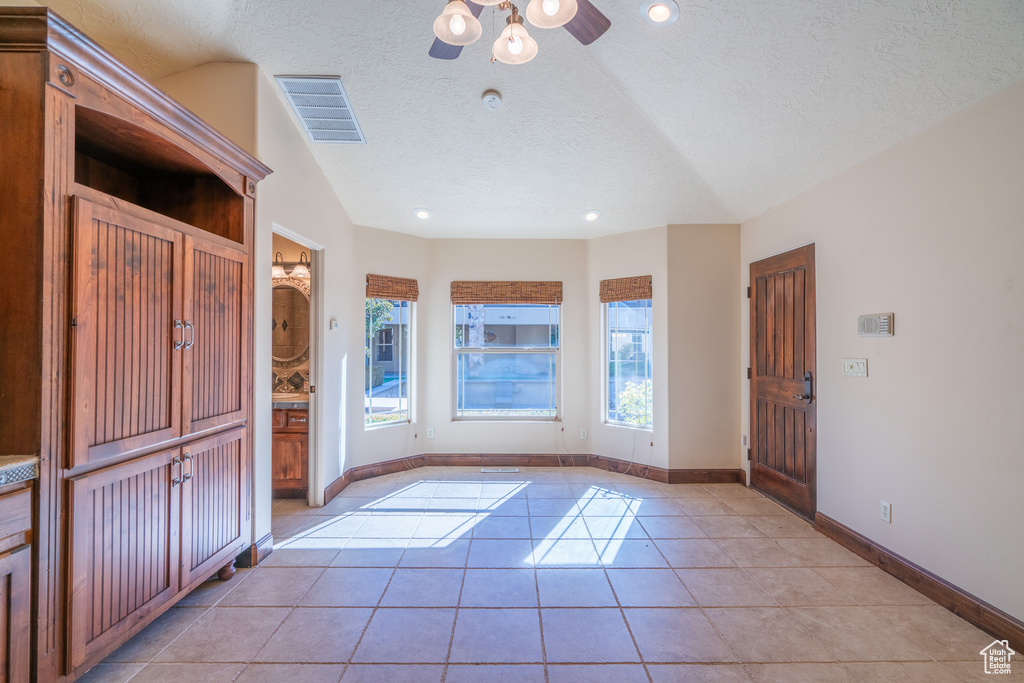 Interior space featuring light tile flooring, ceiling fan, a textured ceiling, and vaulted ceiling