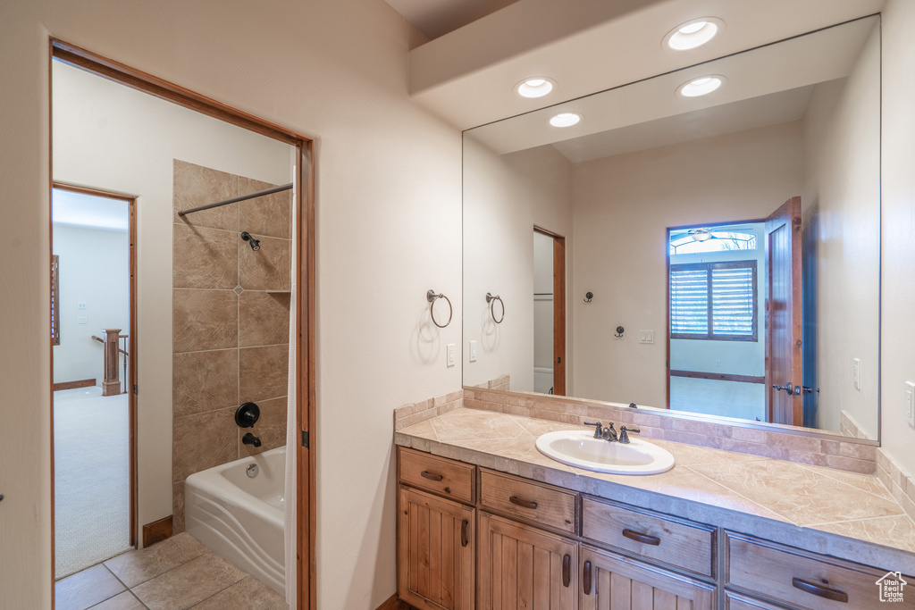 Bathroom featuring large vanity, tile floors, and tiled shower / bath combo