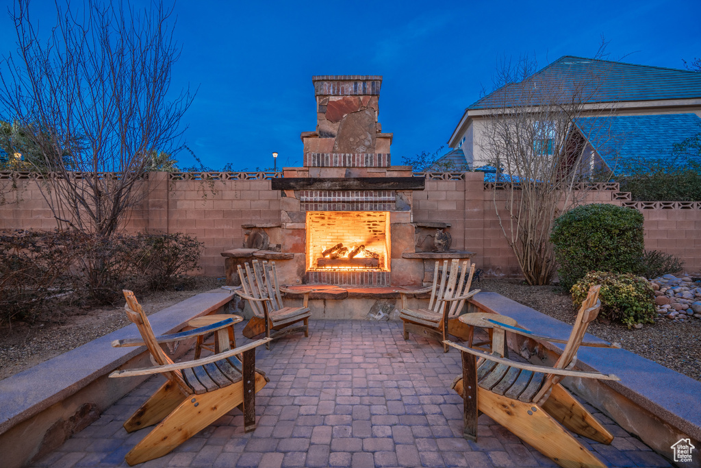 Patio terrace at night featuring exterior fireplace