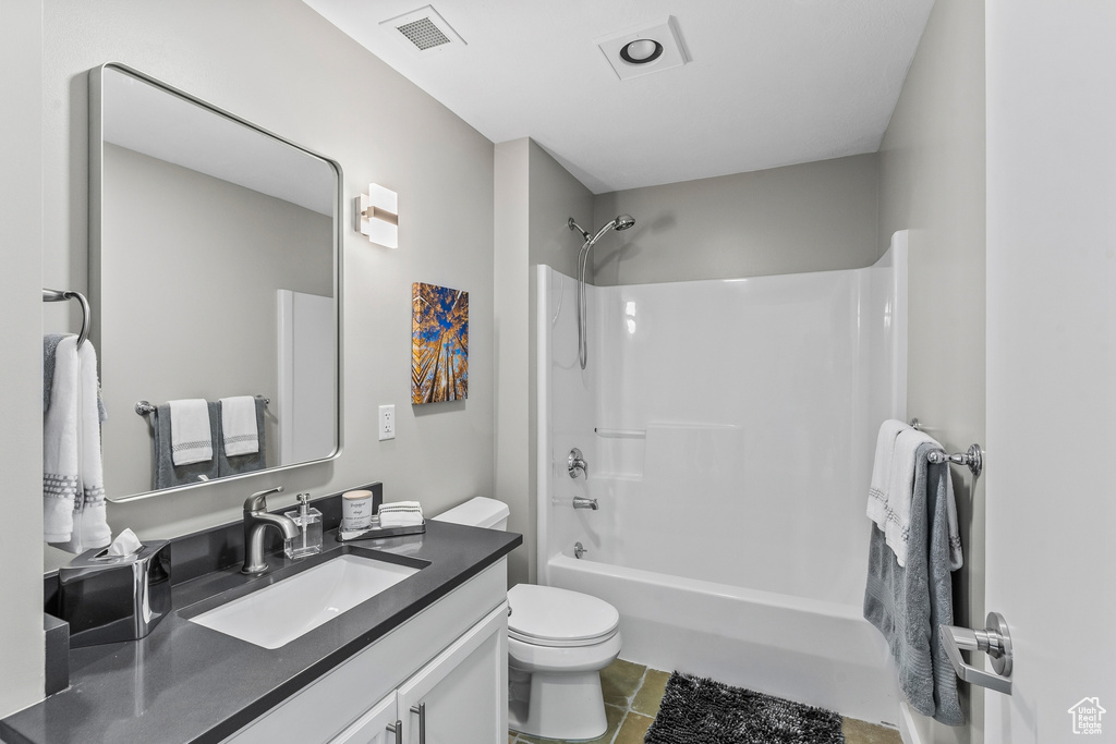 Full bathroom featuring vanity, toilet,  shower combination, and tile flooring