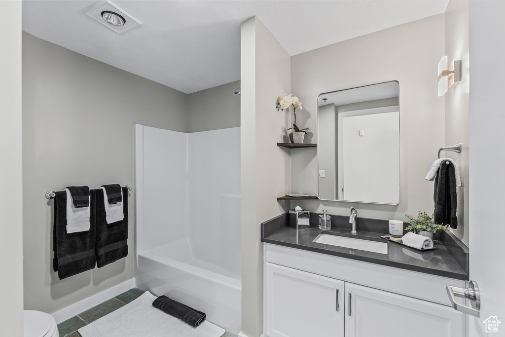 Full bathroom with washtub / shower combination, tile floors, vanity, and toilet