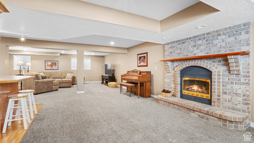 Carpeted living room with a textured ceiling and a brick fireplace