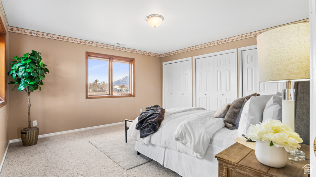 Bedroom with light colored carpet and two closets