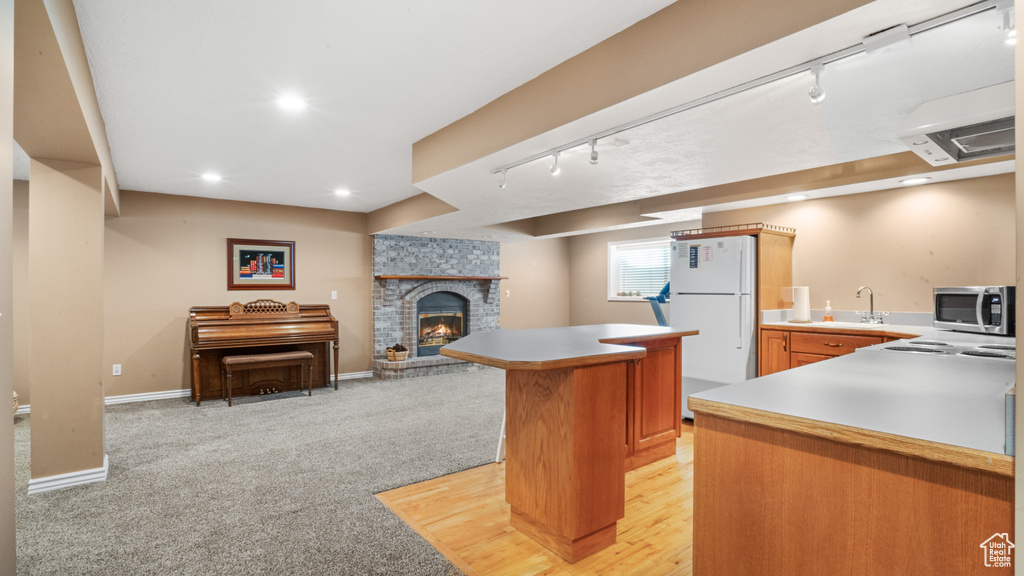Kitchen featuring a fireplace, light colored carpet, sink, white refrigerator, and track lighting