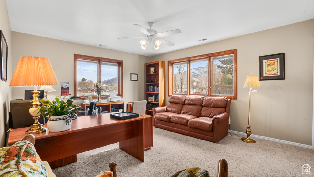 Carpeted home office featuring plenty of natural light and ceiling fan