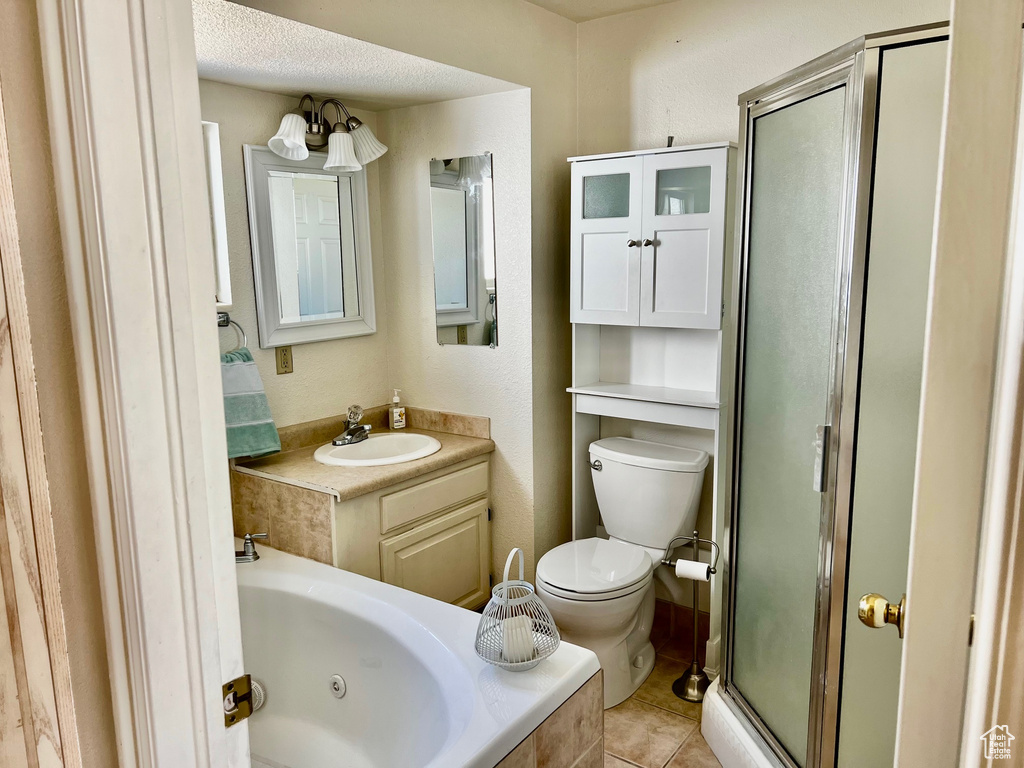 Full bathroom featuring plus walk in shower, vanity, a textured ceiling, toilet, and tile flooring