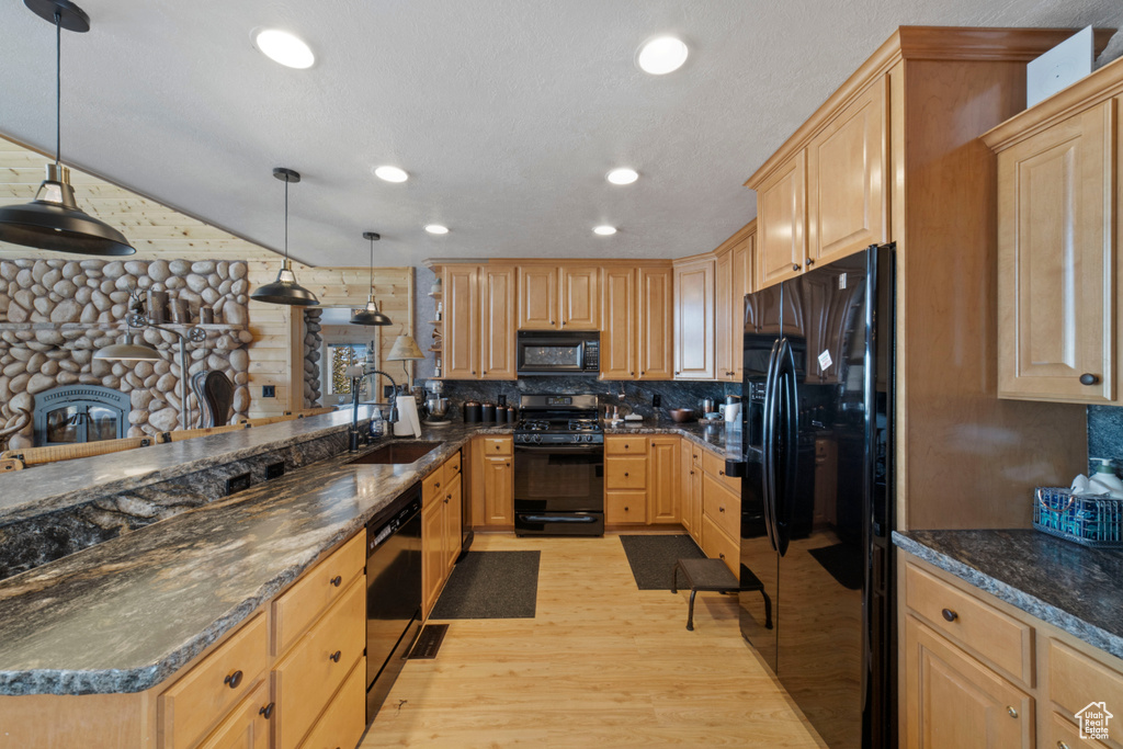 Kitchen with light hardwood / wood-style floors, light brown cabinets, black appliances, tasteful backsplash, and sink