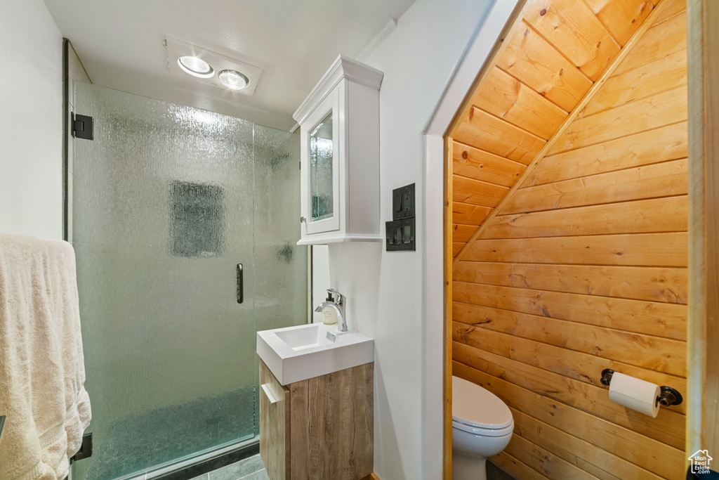 Bathroom featuring wood ceiling, a shower with door, wooden walls, and toilet
