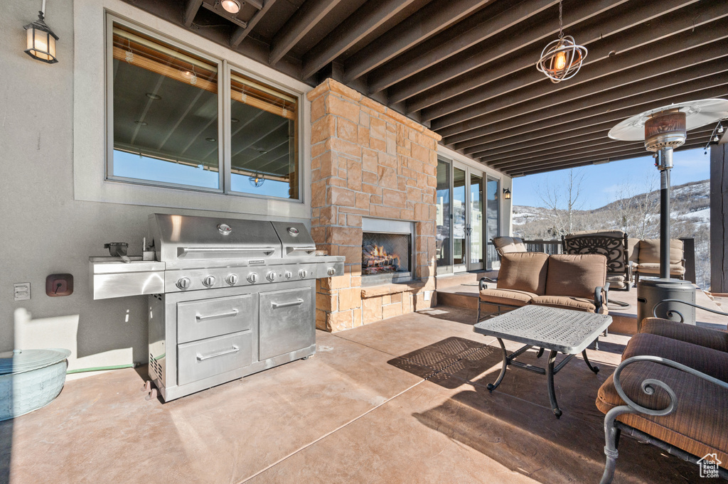 View of terrace featuring a fireplace, a grill, and a mountain view
