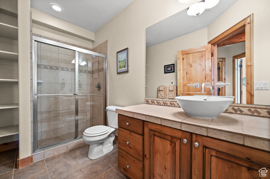 Bathroom featuring vanity, toilet, a shower with door, and tile floors