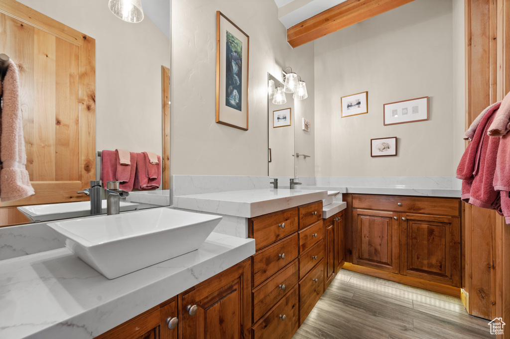 Bathroom with double vanity, beam ceiling, and wood-type flooring