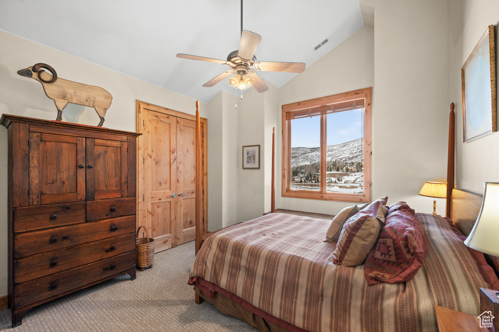 Carpeted bedroom with lofted ceiling, ceiling fan, a mountain view, and a closet