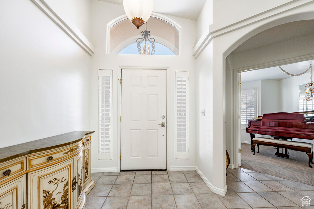 Entrance foyer with an inviting chandelier, a towering ceiling, and light tile floors
