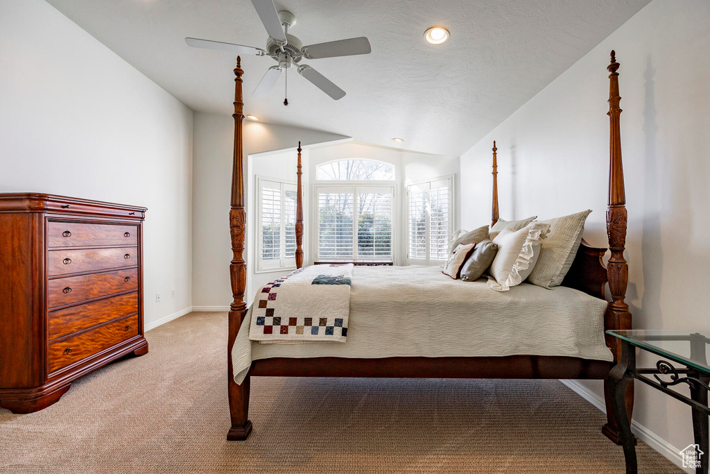 Bedroom with ceiling fan, light colored carpet, and lofted ceiling
