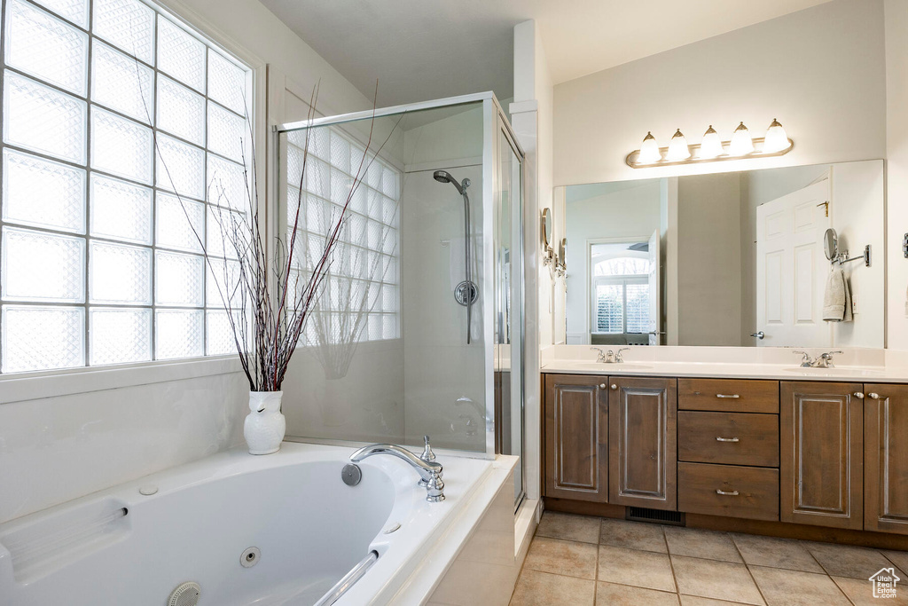 Bathroom featuring a wealth of natural light, double sink, vanity with extensive cabinet space, and tile flooring