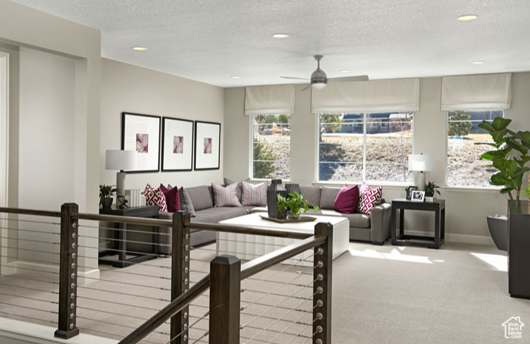 Living room with ceiling fan, light colored carpet, and a textured ceiling