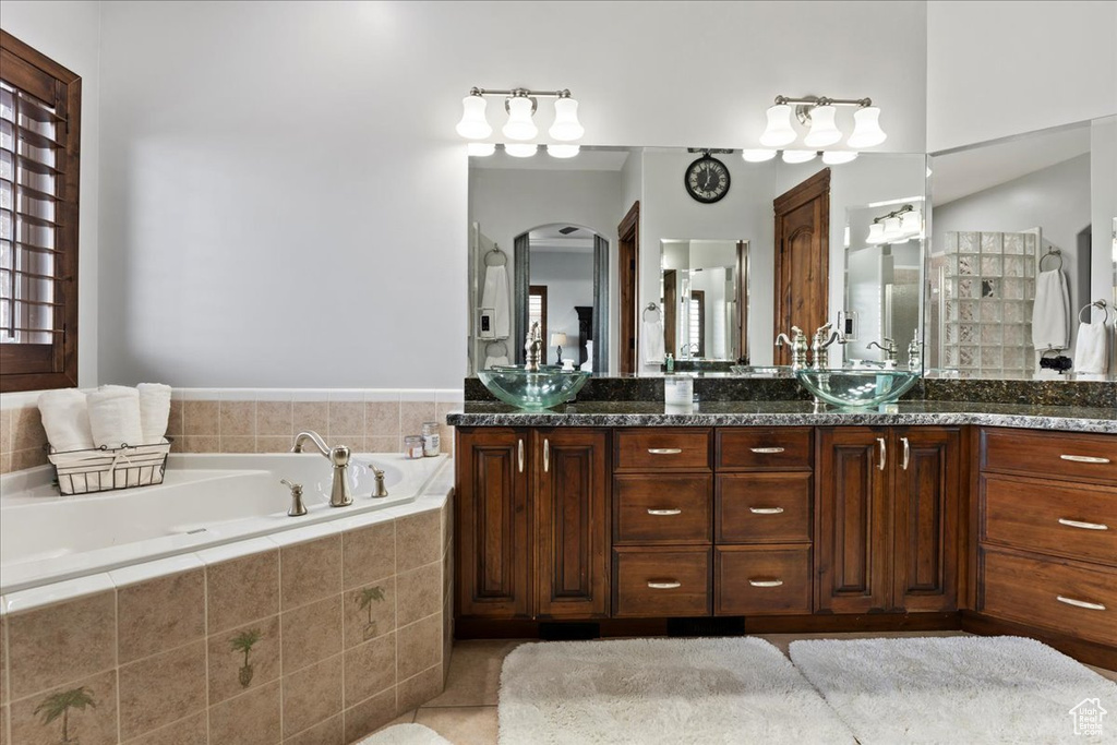 Bathroom featuring tiled tub, tile floors, and dual bowl vanity