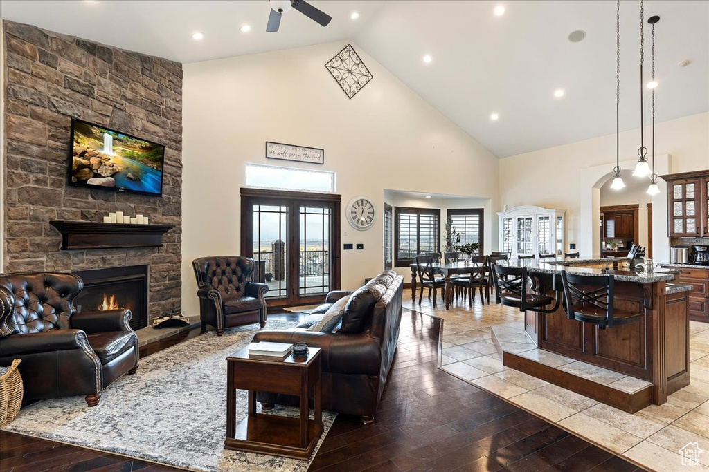 Living room featuring french doors, high vaulted ceiling, a fireplace, light tile floors, and ceiling fan