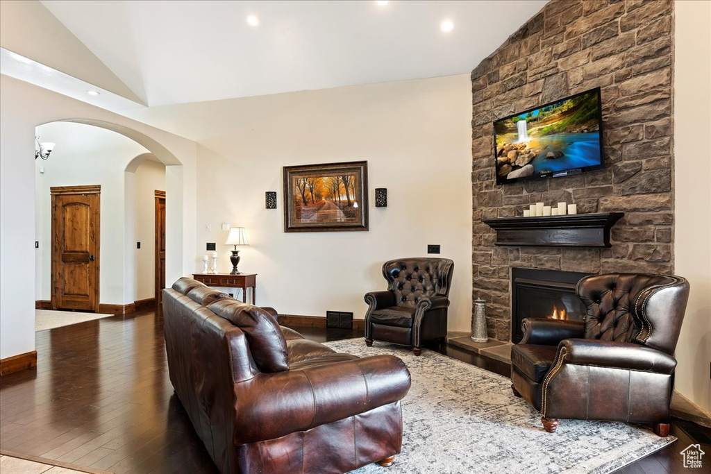 Living room featuring a stone fireplace, dark hardwood / wood-style floors, and vaulted ceiling