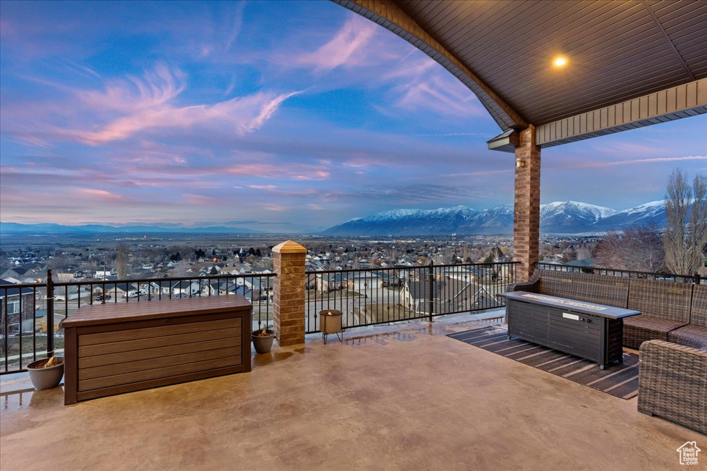 Patio terrace at dusk featuring a mountain view and a balcony