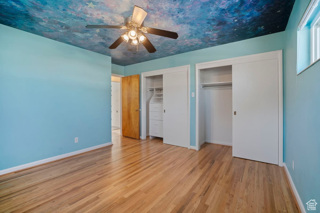Unfurnished bedroom with two closets, light hardwood / wood-style flooring, and ceiling fan