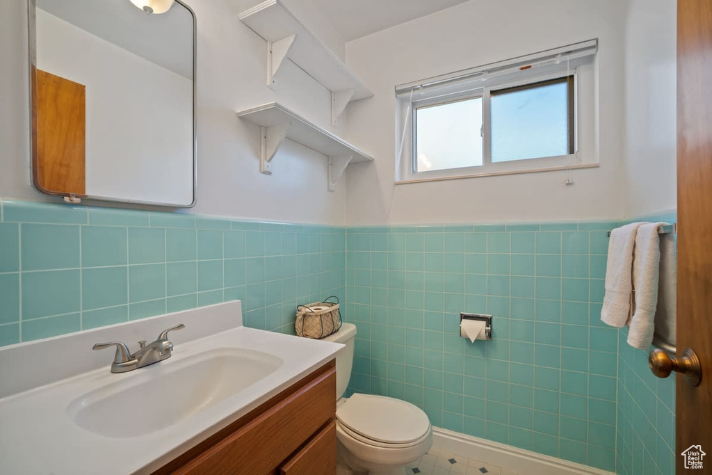 Bathroom with toilet, tile walls, tile floors, and backsplash