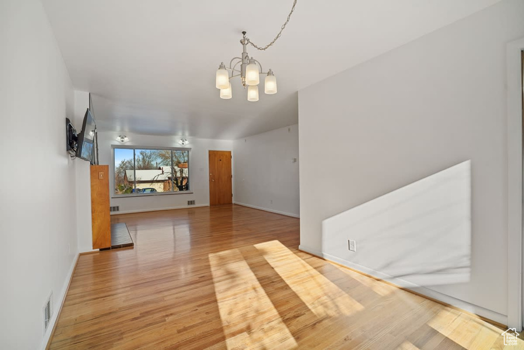 Empty room featuring light hardwood / wood-style floors and an inviting chandelier