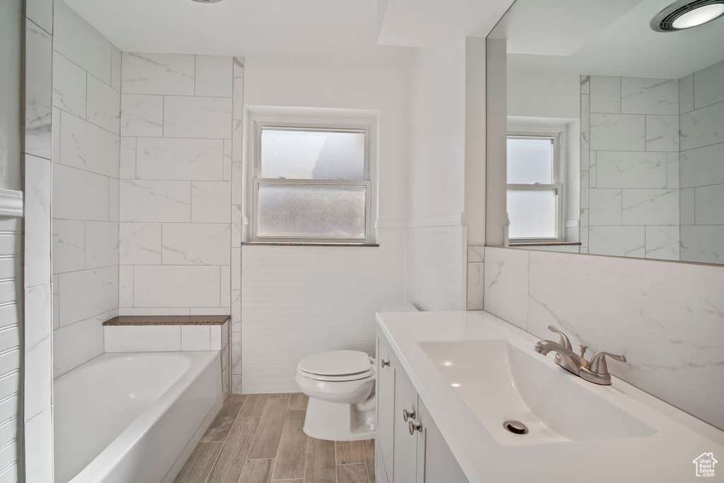 Bathroom with vanity, toilet, hardwood / wood-style floors, and tile walls